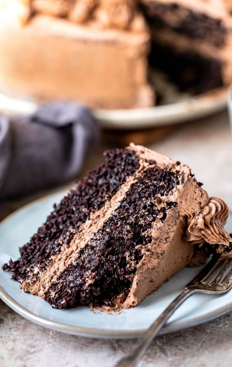 A slice of chocolate cake with cream frosting and filling. 