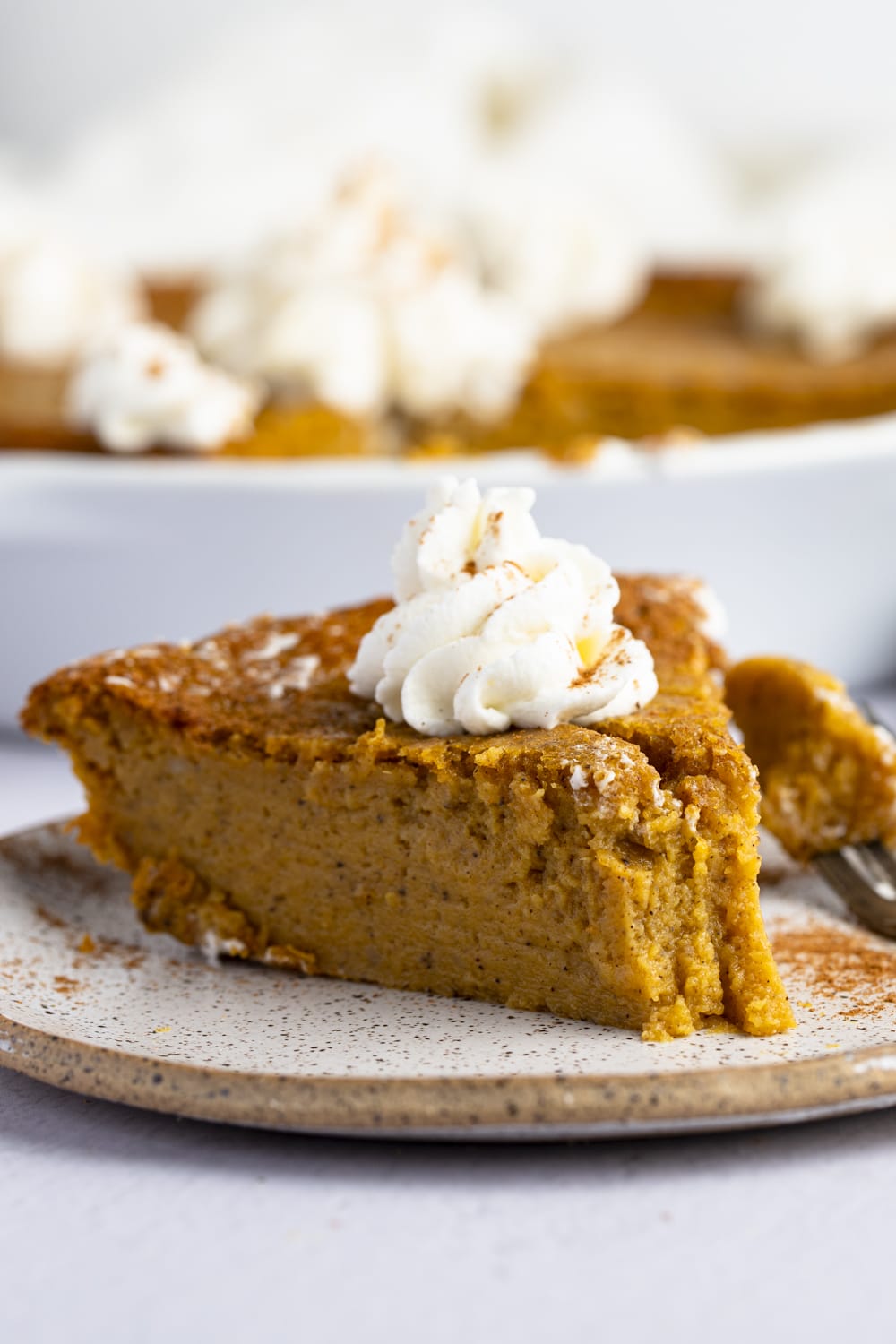 A slice of pumpkin pie with whip cream on top.