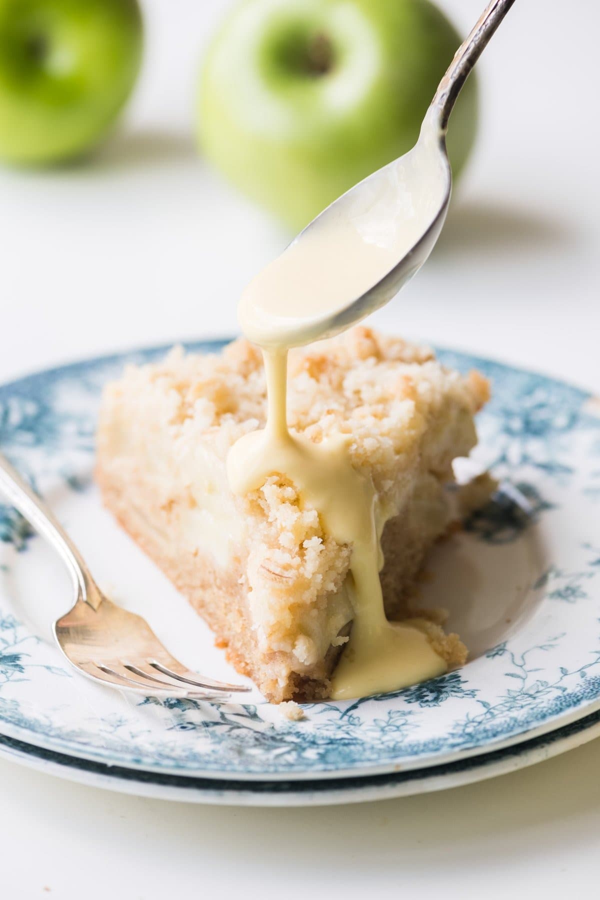 Slice of apple cake drizzled with custard sauce. 