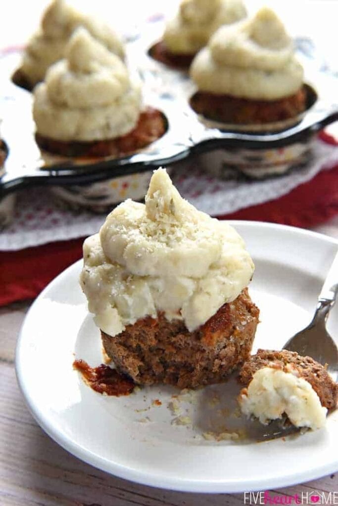 Meatloaf cupcakes served on a plate topped with mashed potatoes. 
