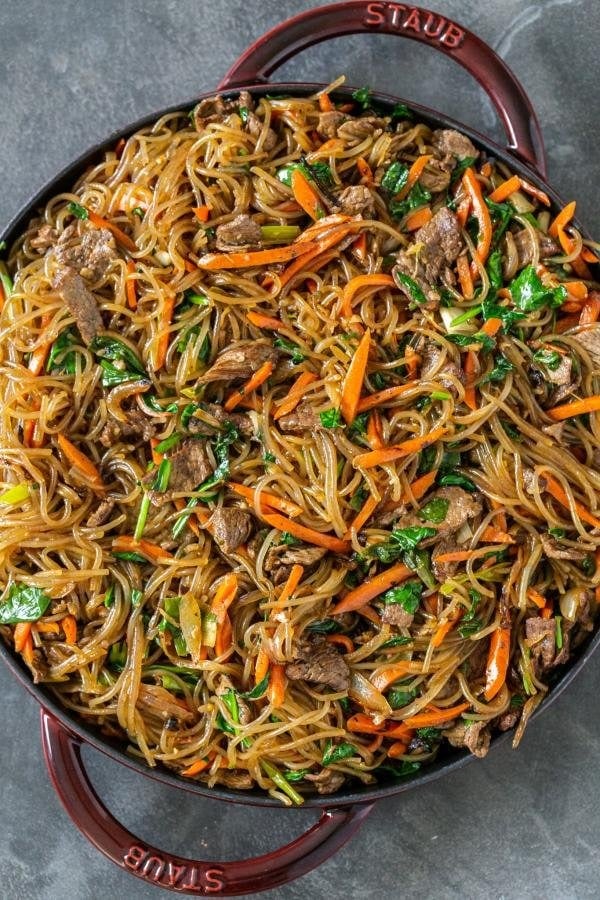 Stir fried glass noodles with veggies and meat on a pan.