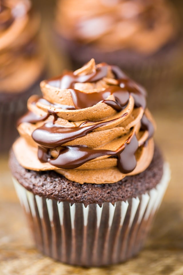 Chocolate cupcakes topped with buttercream frosting and a drizzle of chocolate syrup. 
