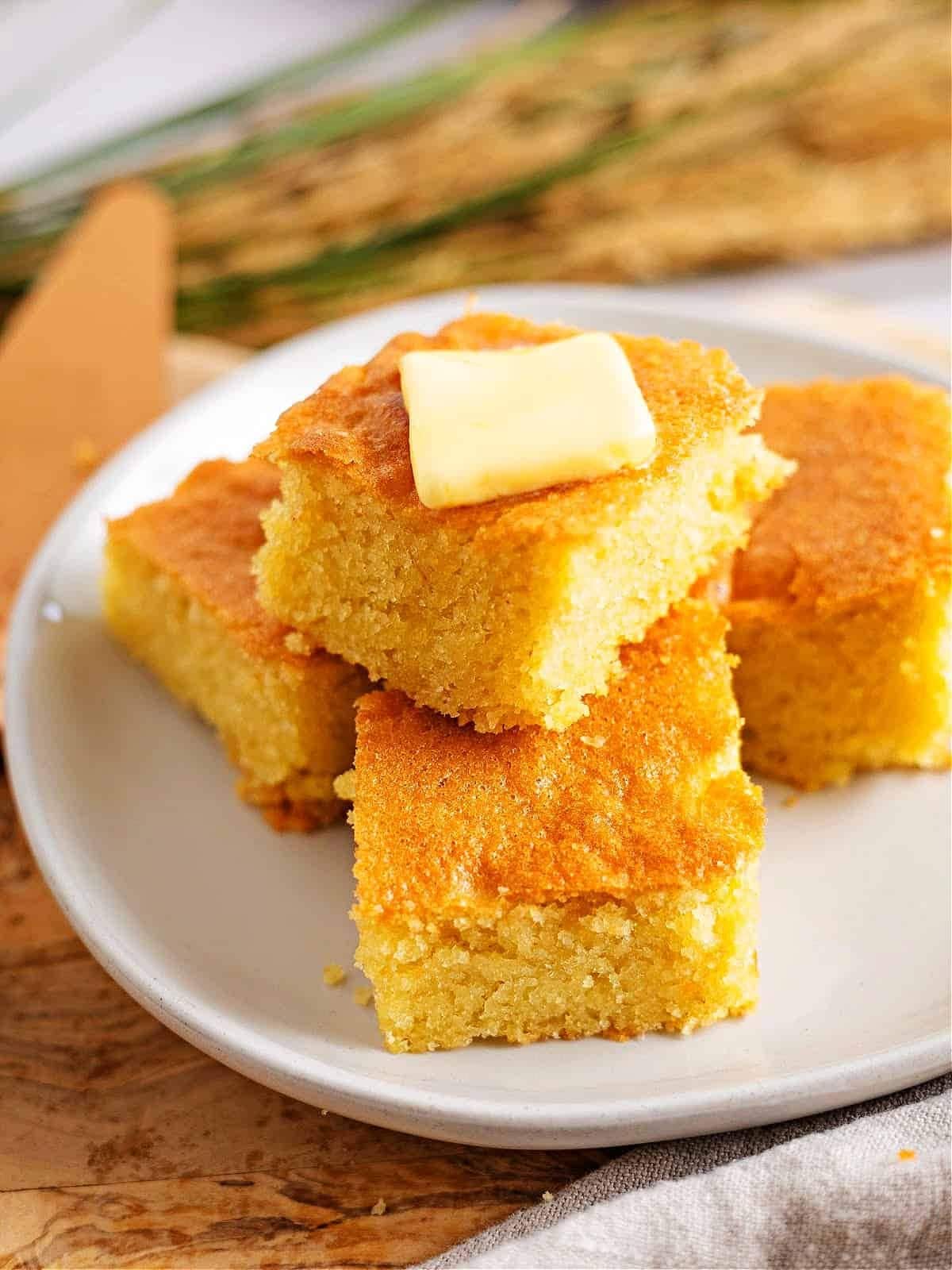 Stack slices of cornbread topped with a piece of butter.