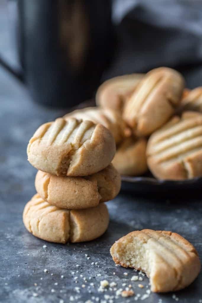 Bunch of bite size butter cookies stack on a concrete surface.