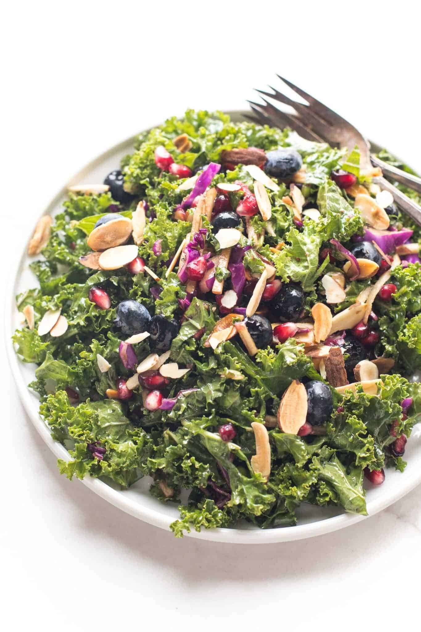 kale salad with with kale, blueberries, onions, pomegranate, apples, and sliced almonds. 