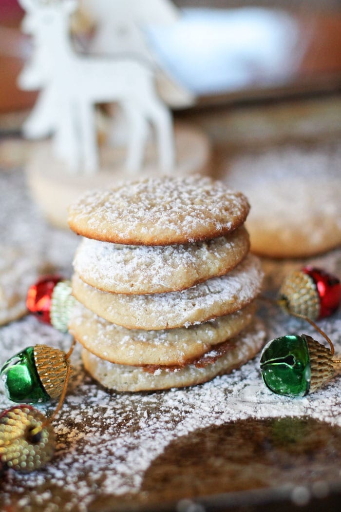 Cheesecake cookies dusted with powdered sugar stack on a holiday table.