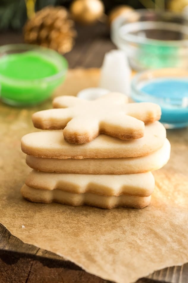 Shaped sugar cookies stack top of a parchment paper.