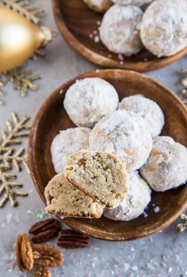 Bunch of pecan snowball cookies on a wooden bowl.