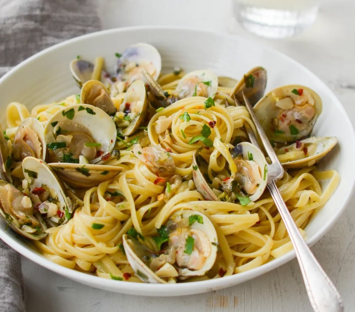 Linguini pasta with clams on plate with fork. 