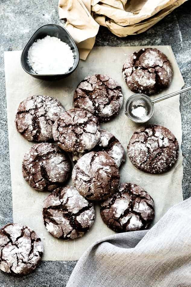 Crinkle cookies coated with powdered sugar on a parchment paper. 
