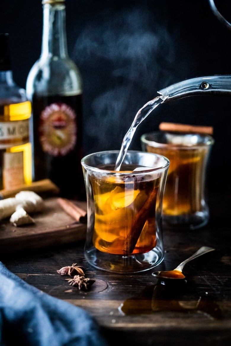 Hot toddy drinks on shot glass garnished with cinnamon sticks, star anise and tea bags. 