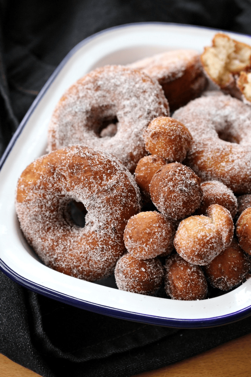 Bunch of doughnuts covered with white sugar in a pan. 