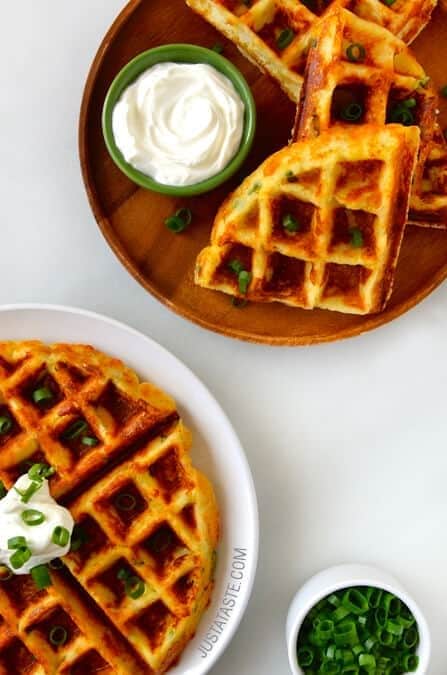 Potato waffles served with cream and chopped onion leaves on top. 