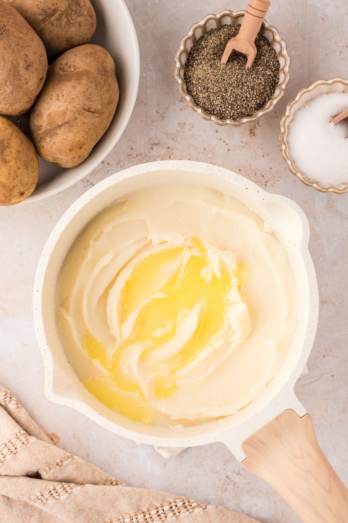 Mashed potato with melted butter on top cooked in a white pot.