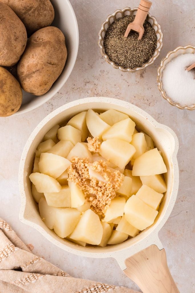 Boiled potatoes with fried minced garlic on top in a pot.