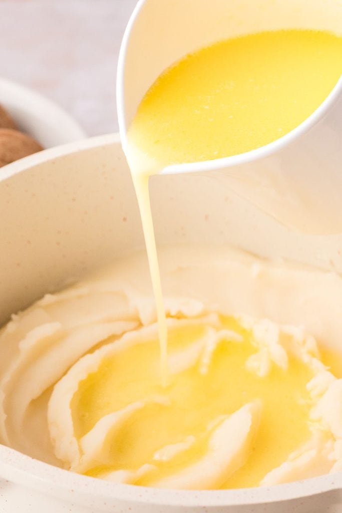 Melted butter poured mashed potatoes in a pot.