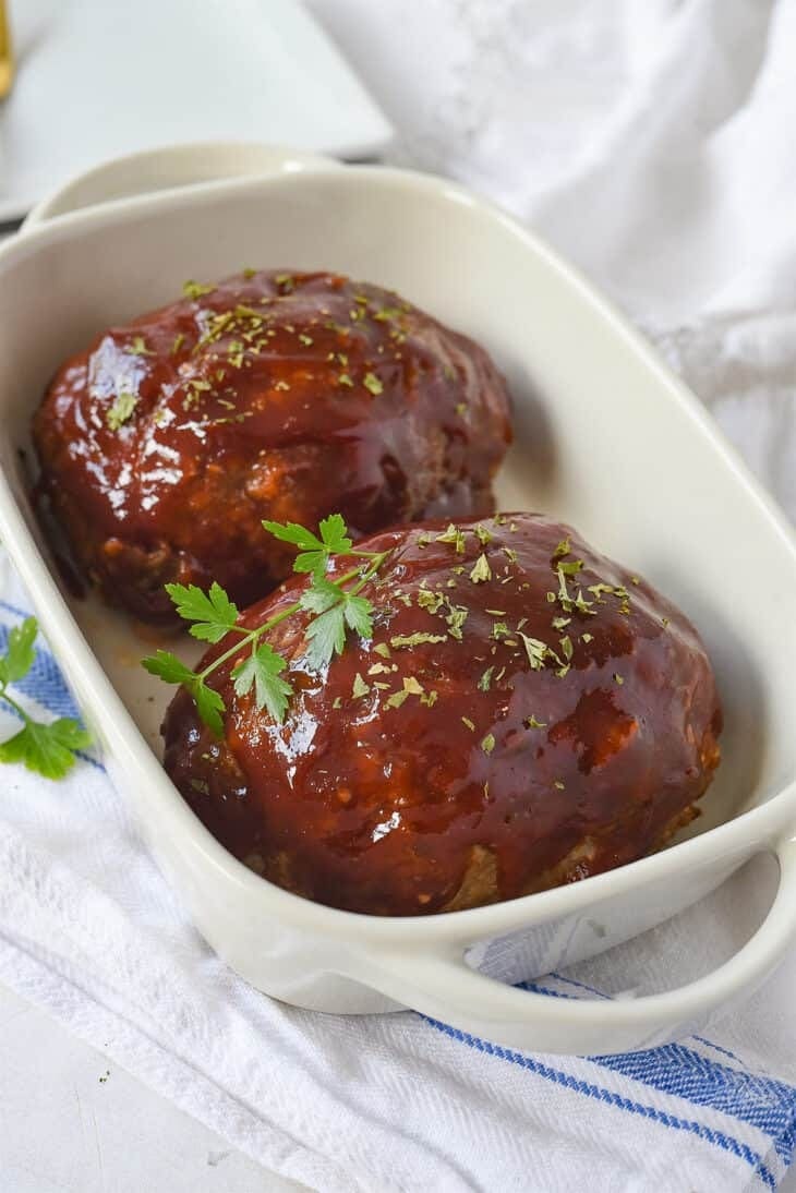 Two pieces meatloaf topped with glaze served on a dish.