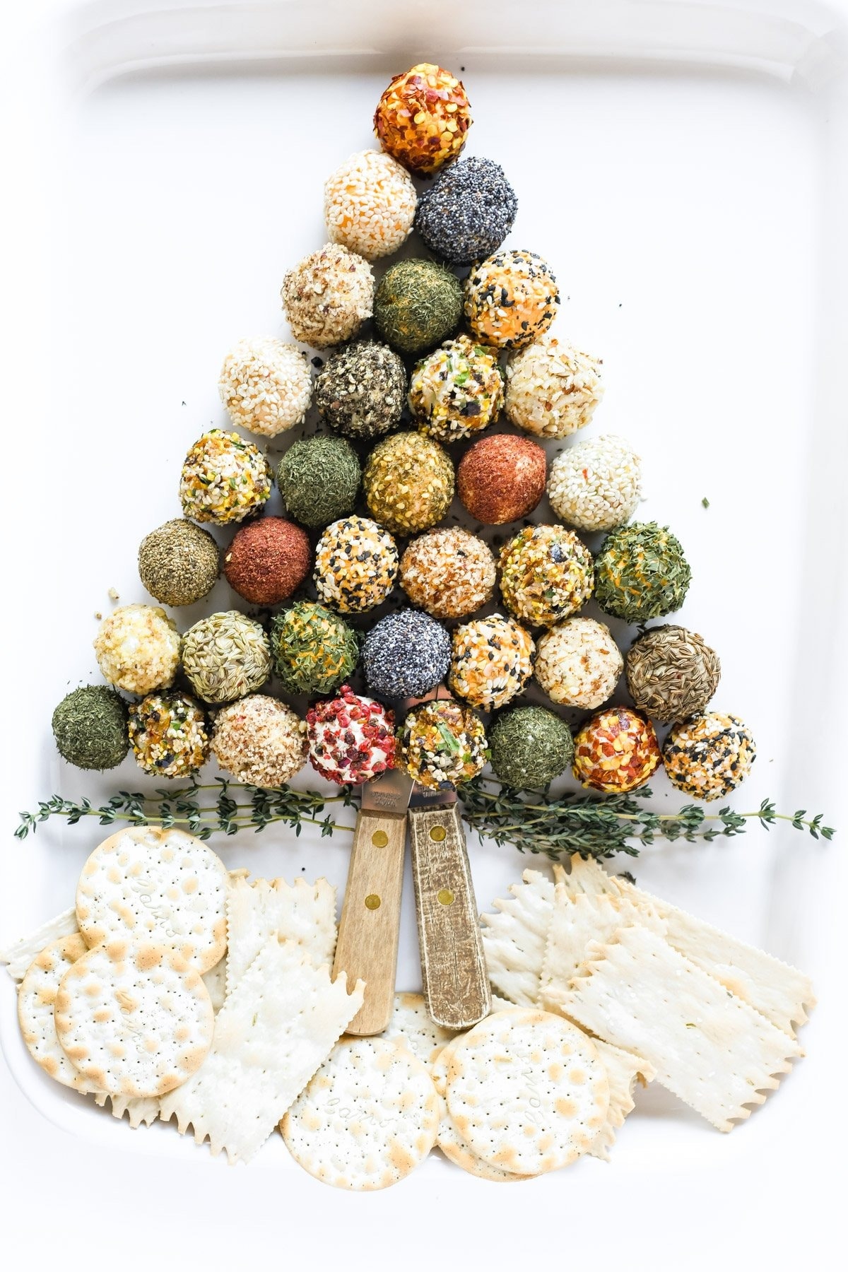 Mini cheeseball coated in different spices and nuts arranged in Christmas tree shape. 
