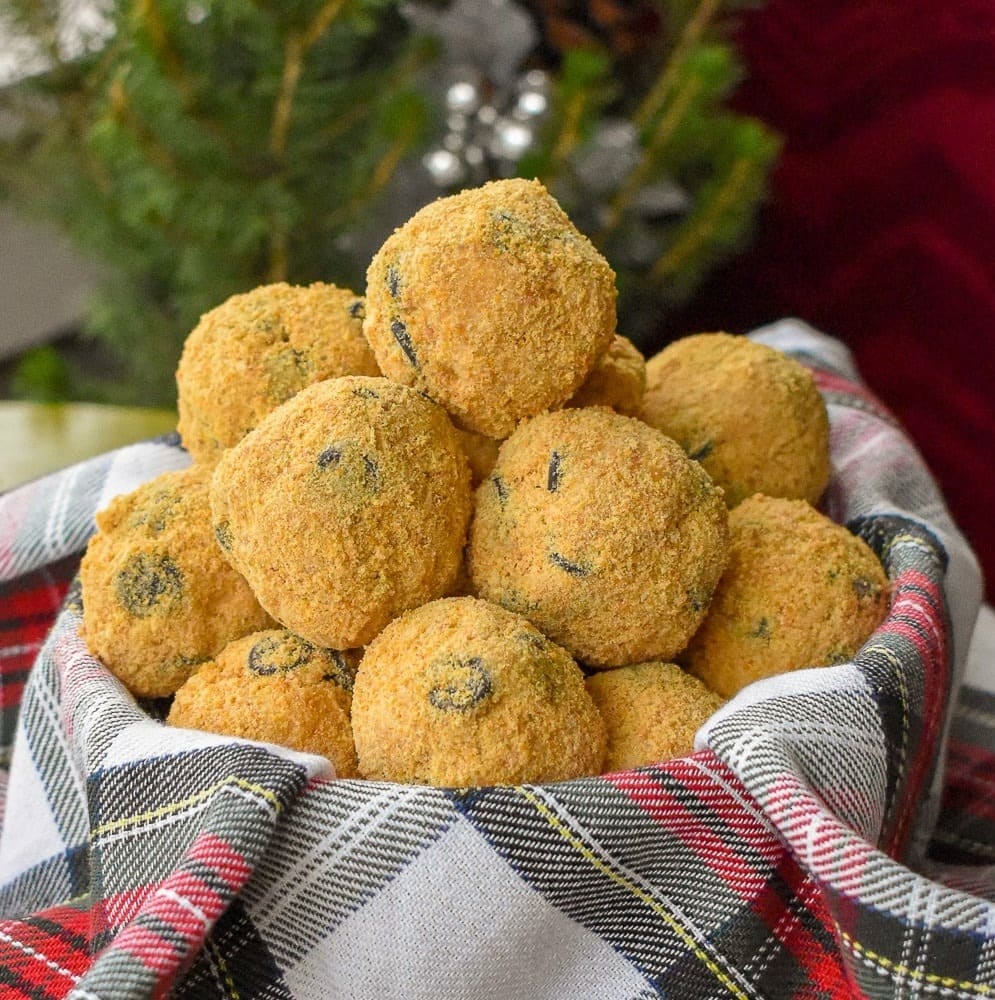 Bunch of crushed graham covered cookie balls on basket with checkered cloth. 