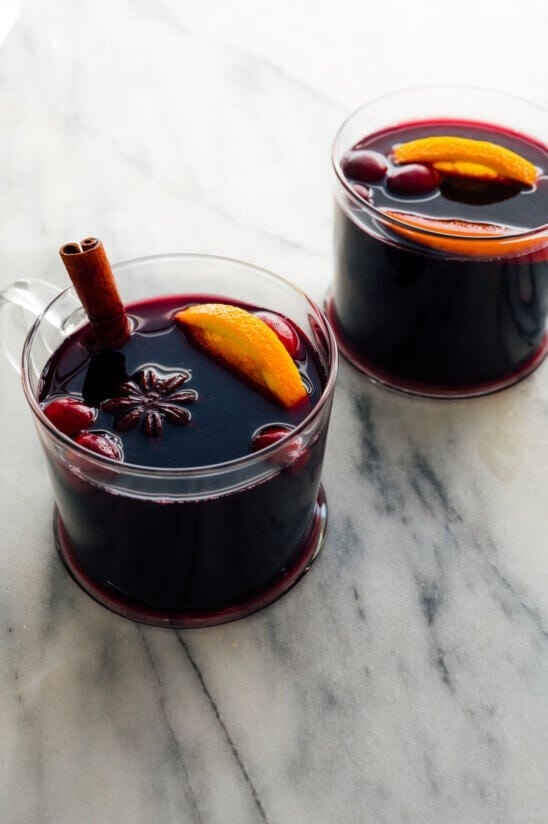Two glasses of mulled wine garnished with cinnamon sticks and lemon slices.