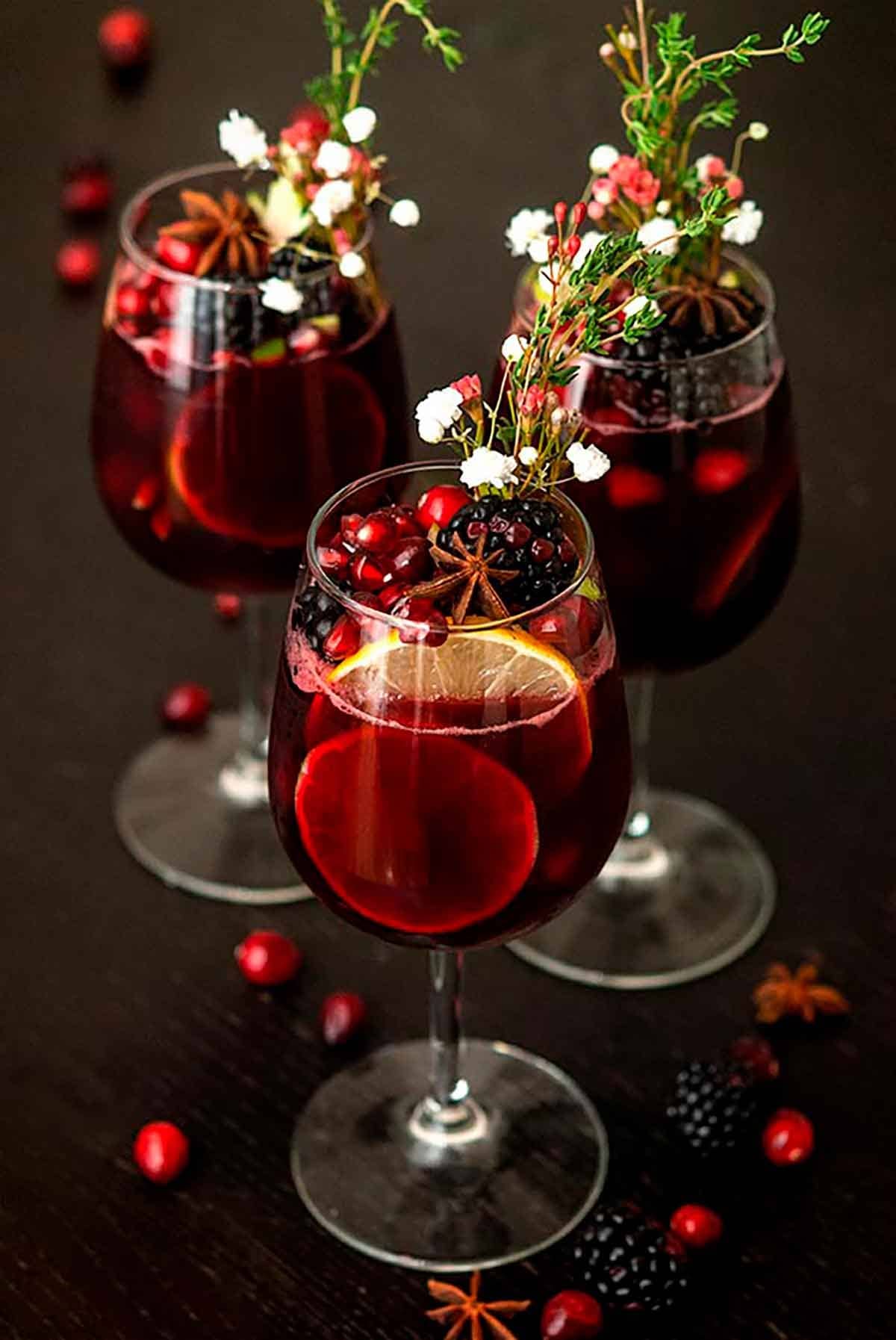 Mulled wine sangria on glass garnished with raspberries, cranberries and orange slices. 