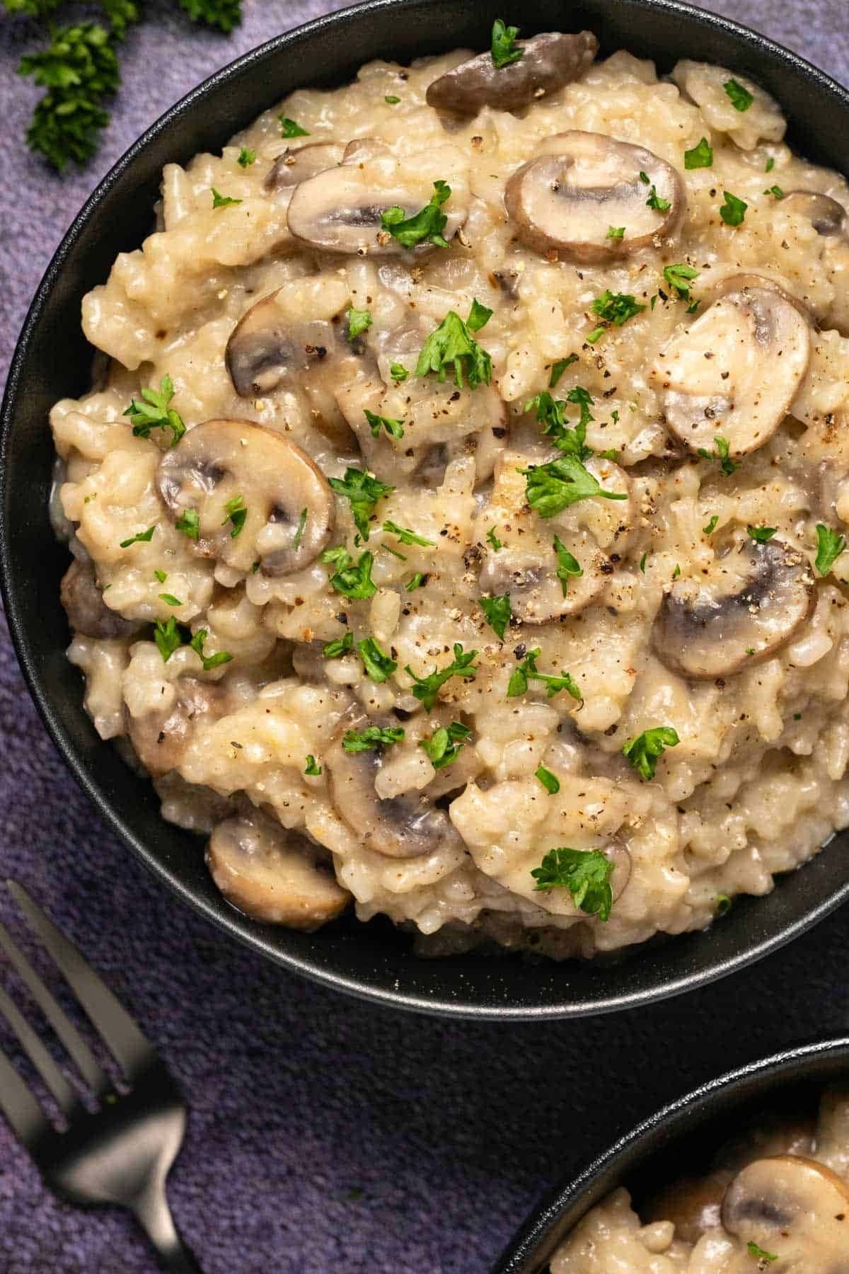 Bowl of mushroom risotto garnished with chopped parsley leaves. 