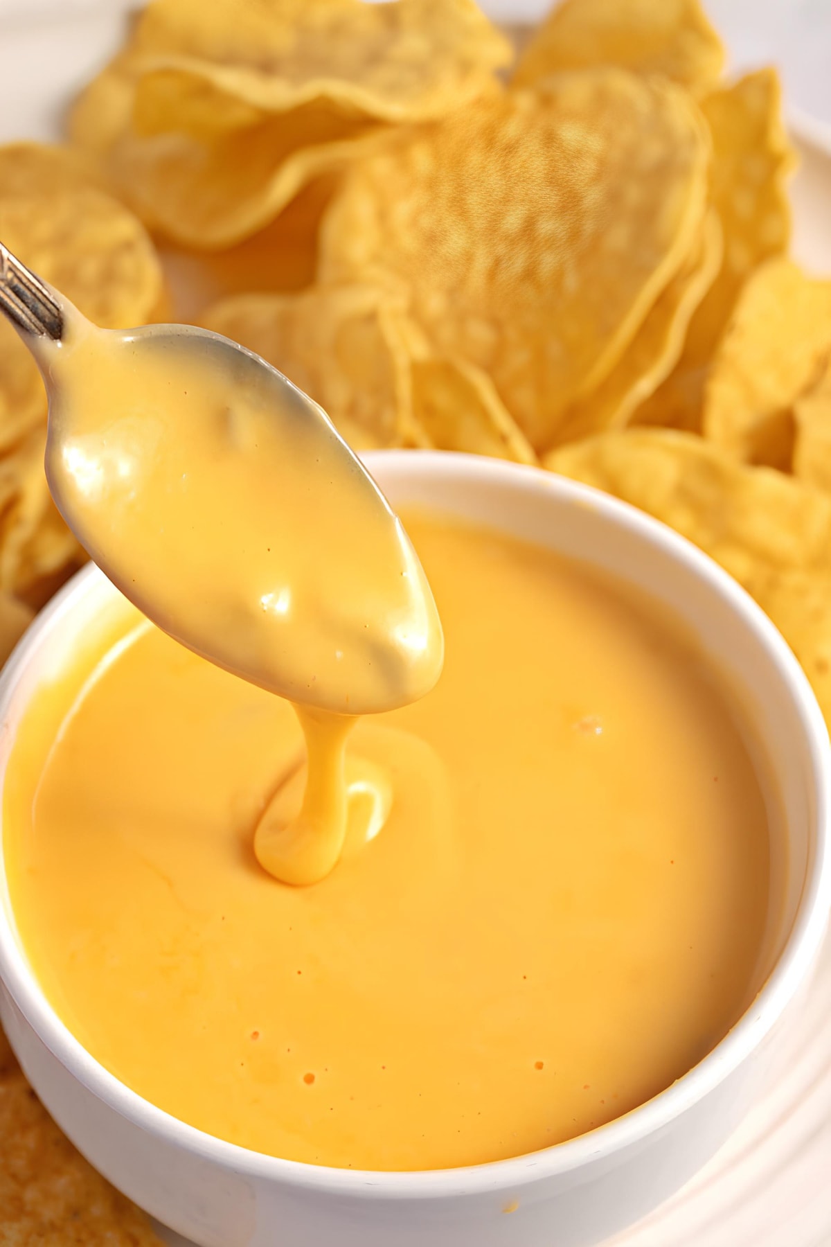 A creamy and savory nacho cheese sauce in a bowl with chips