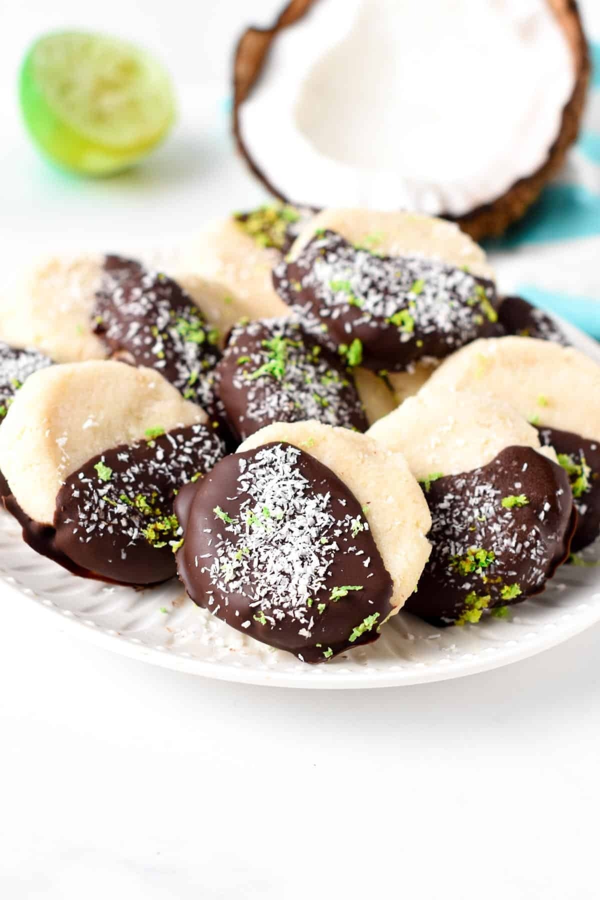 Coconut cookies half dipped in melted chocolate garnished with shredded coconut.