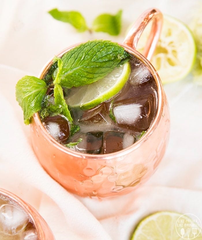 Moscow mule in a glass filled with ice and garnished with sliced lemon and mint. 
