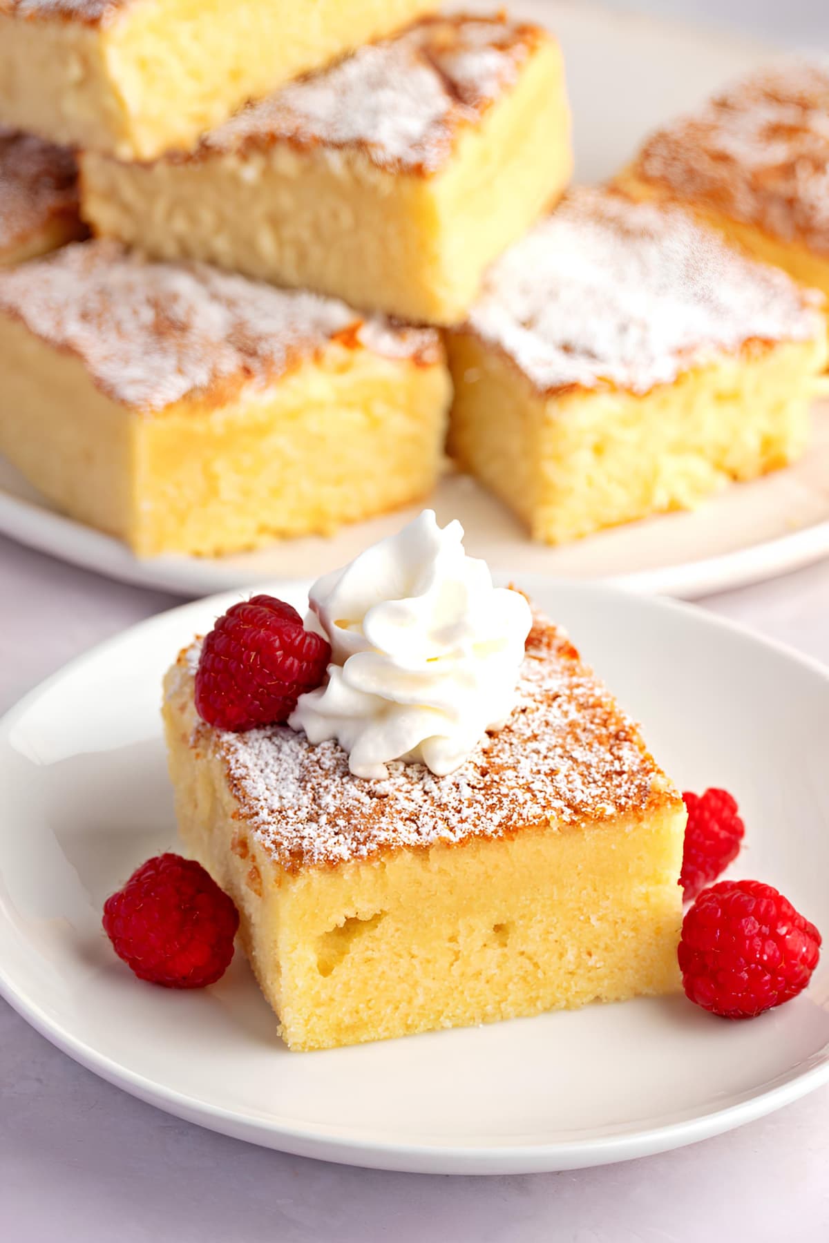 Old-Fashioned Hot Milk Cake Recipe: A slice of hot milk cake topped with whipped cream and garnished with fresh raspberries.