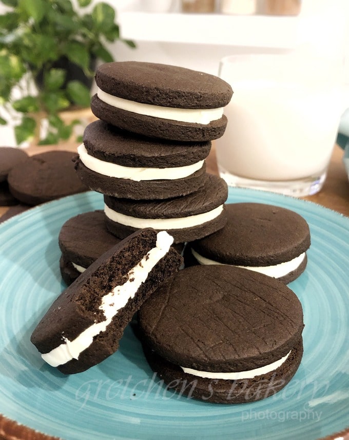 Bunch of chocolate cookies with cream filling piled on a plate. 