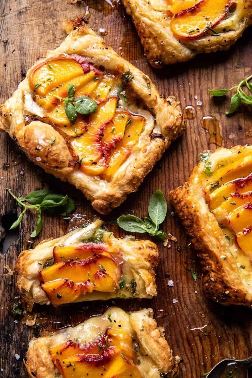 Peach brie pastry tarts with peppered rosemary honey on a wooden board.