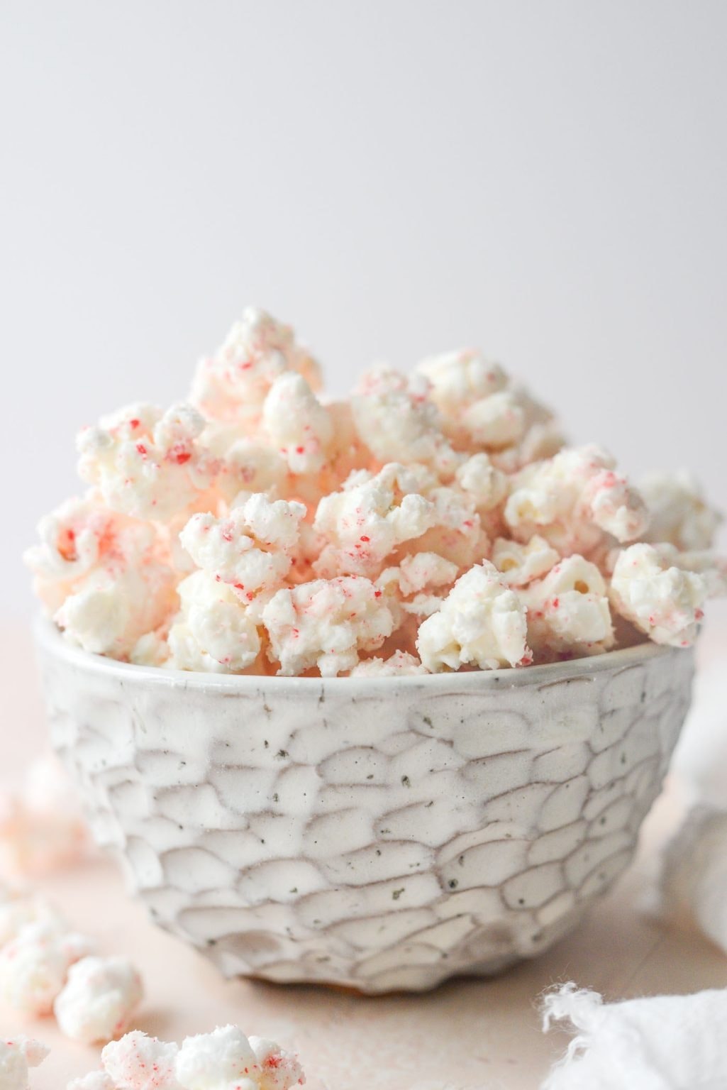 A bowl of white chocolate popcorn dusted with peppermint.