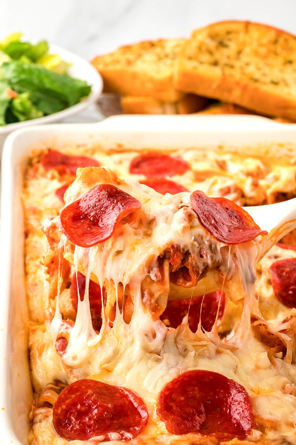 A serving of Pepperoni Pizza Casserole being lifted from a baking dish