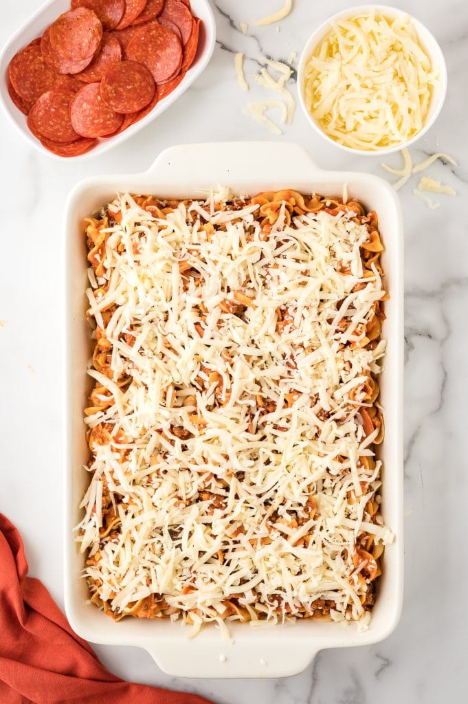 Pre-cooked pepperoni pizza casserole topped with cheese in a baking dish