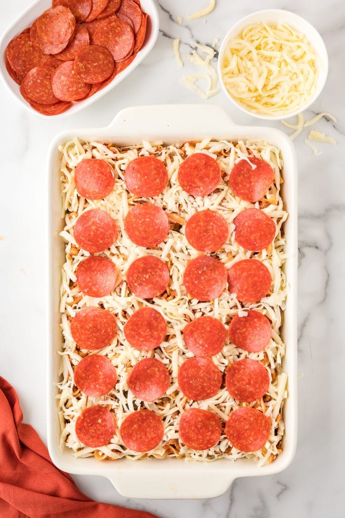 Pre-cooked pizza casserole topped with pepperoni and cheese in a baking dish