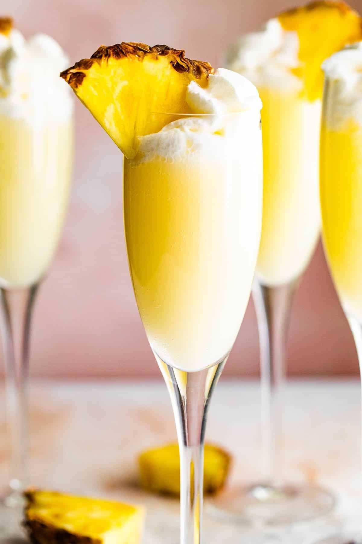 Pineapple mimosa topped with whip cream and fresh pineapple slice garnish. 