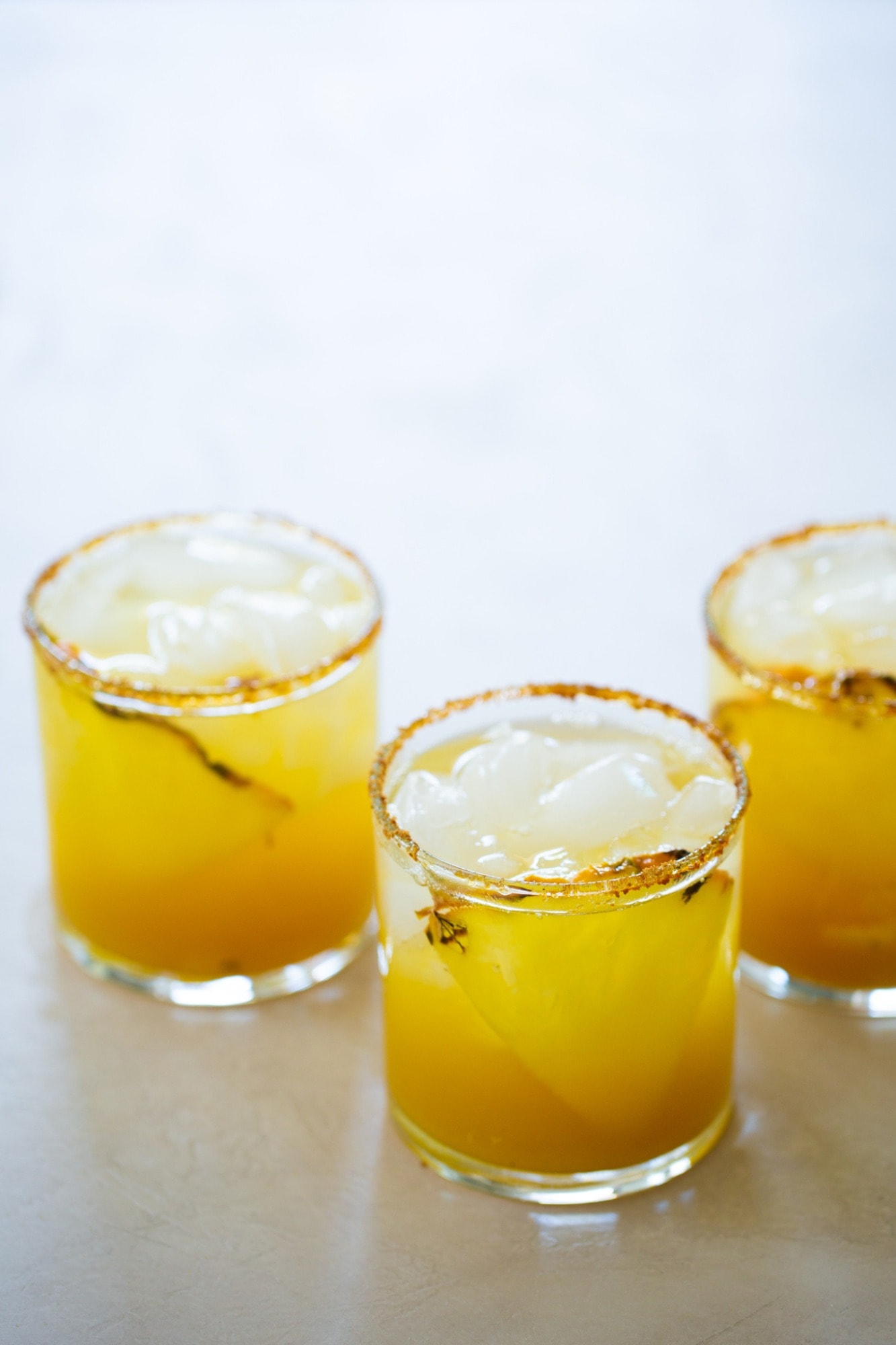 Three glasses of salt rimmed pineapple margarita with.