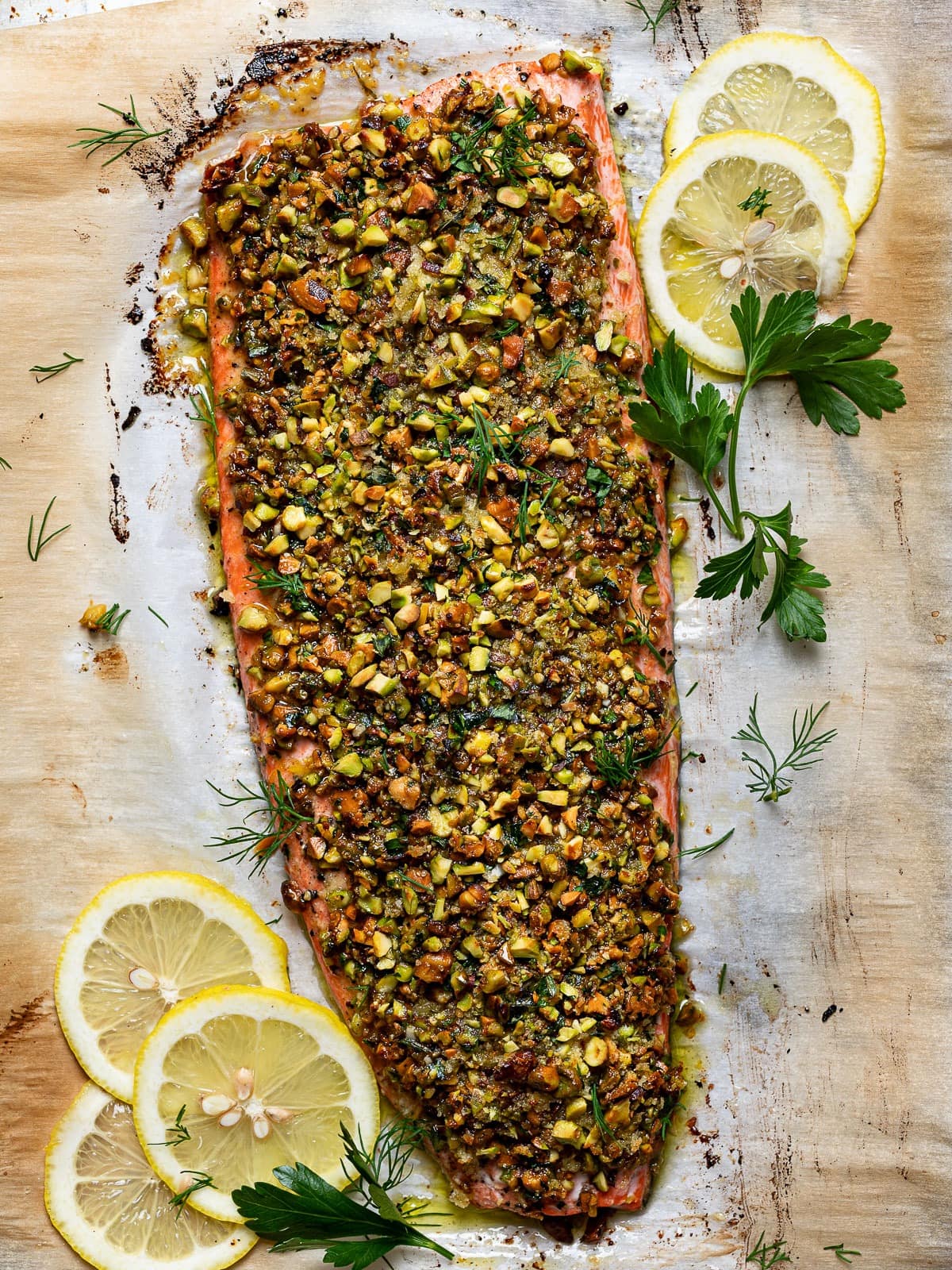 Pistachio crusted salmon on a wooden board garnished with lemon slices. 