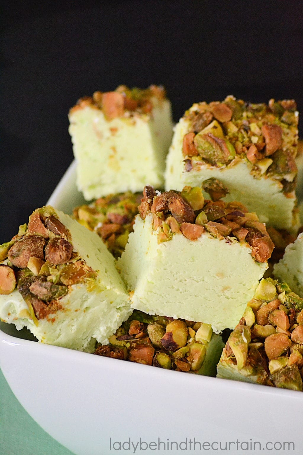 Bunch of green fudge with chopped pistachio on a white bowl. 