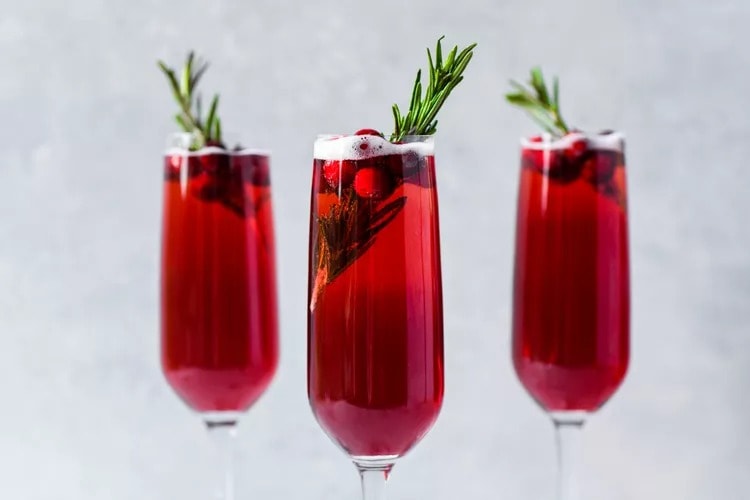 Three glasses of red wine with a sprig of rosemary at holiday parties.