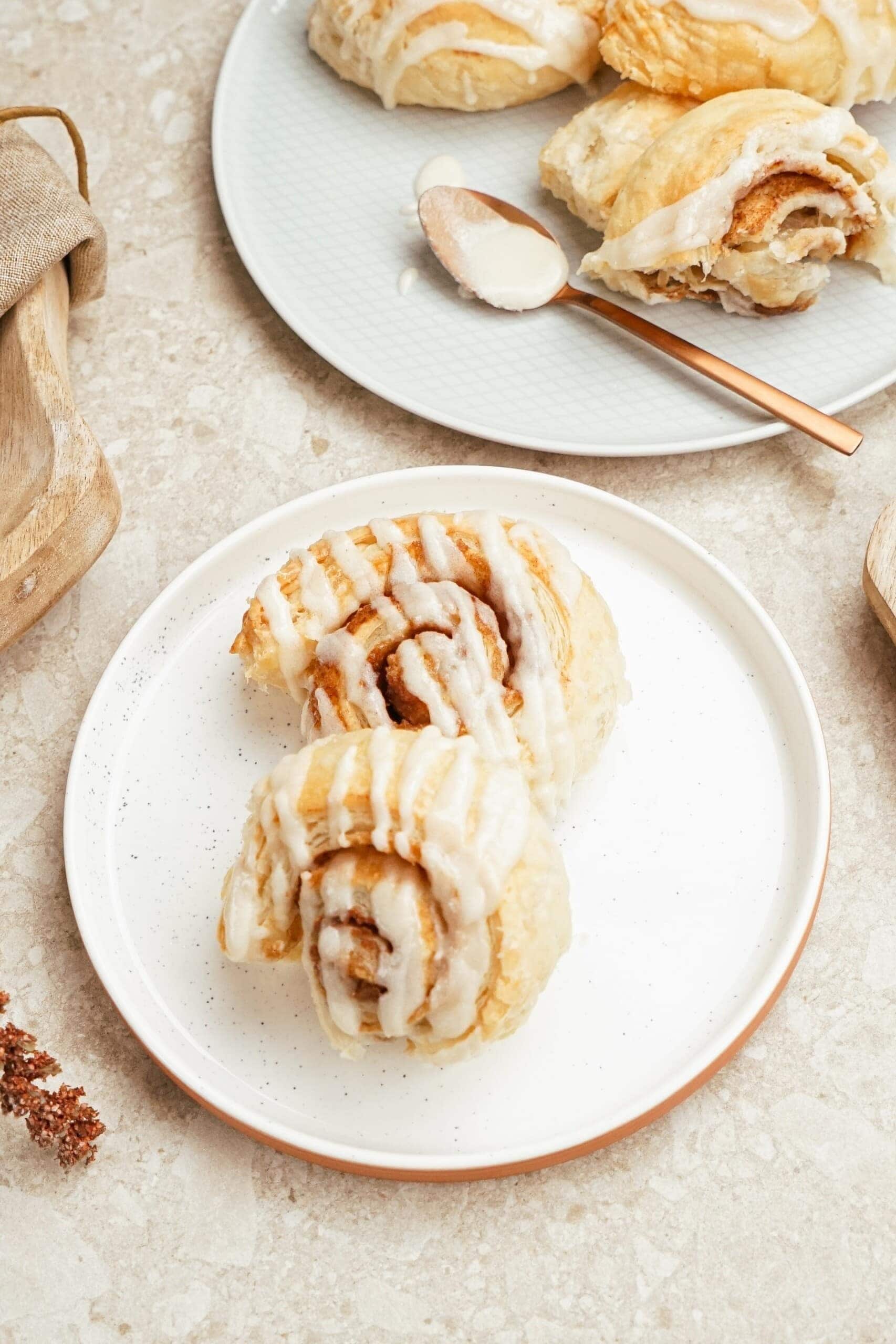 Cinnamon rolls with sugar glazed toppings served on plates. 