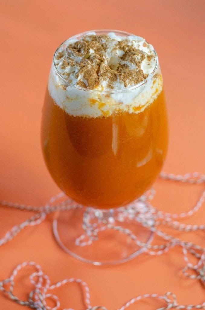 A glass of pumpkin pie punch topped with whipped cream and spices. 