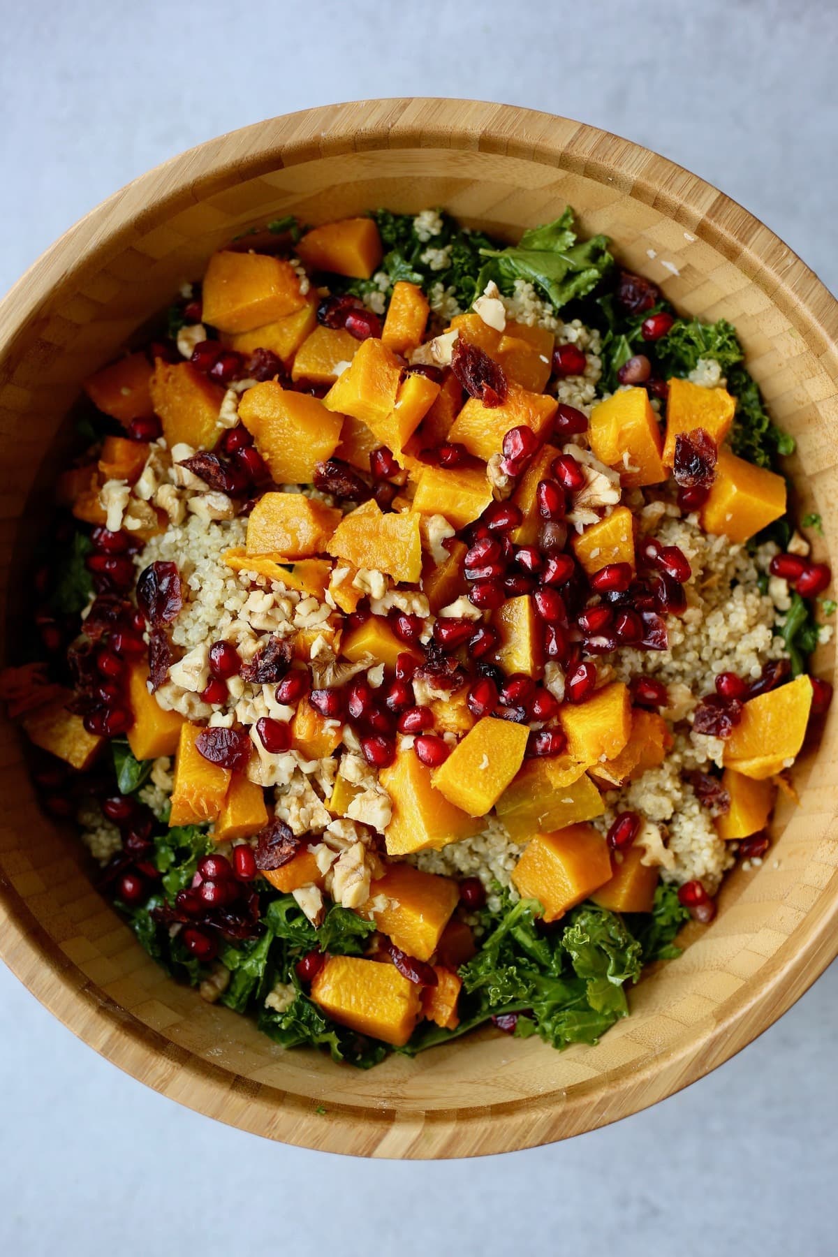 Salad with quinoa, kale, squash and pomegranate in a wooden bowl. 