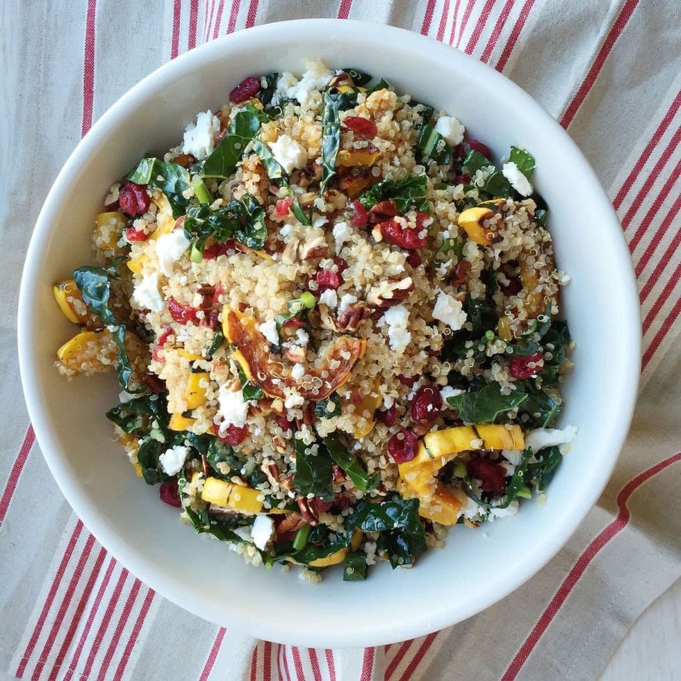 Bowl of quinoa salad with roasted squash, dried cranberries, and pecans