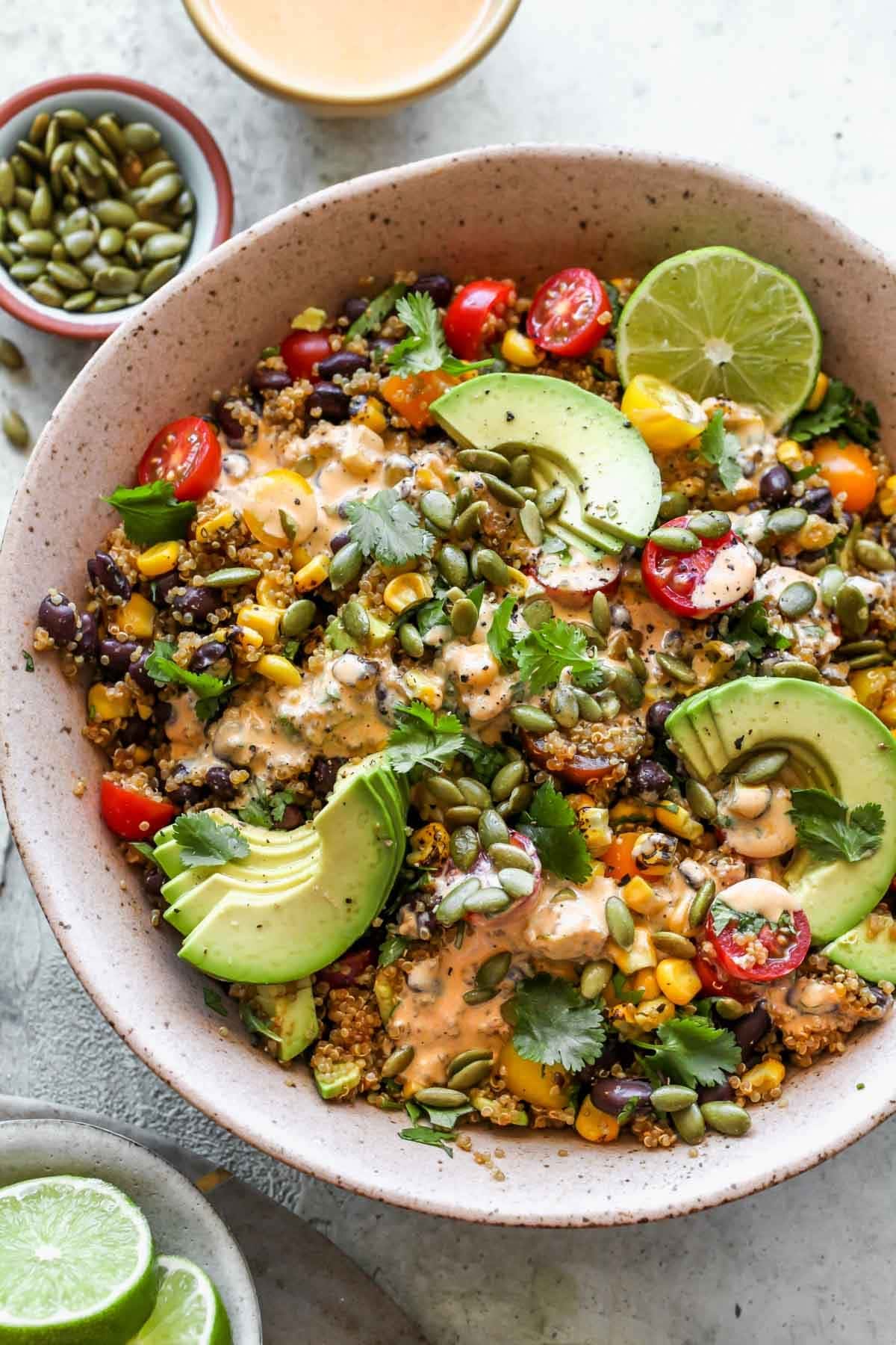 Salad in a bowl made with with black beans, fire-roasted corn, creamy avocado, and ripe tomatoes all tossed with a smoky chipotle dressing..