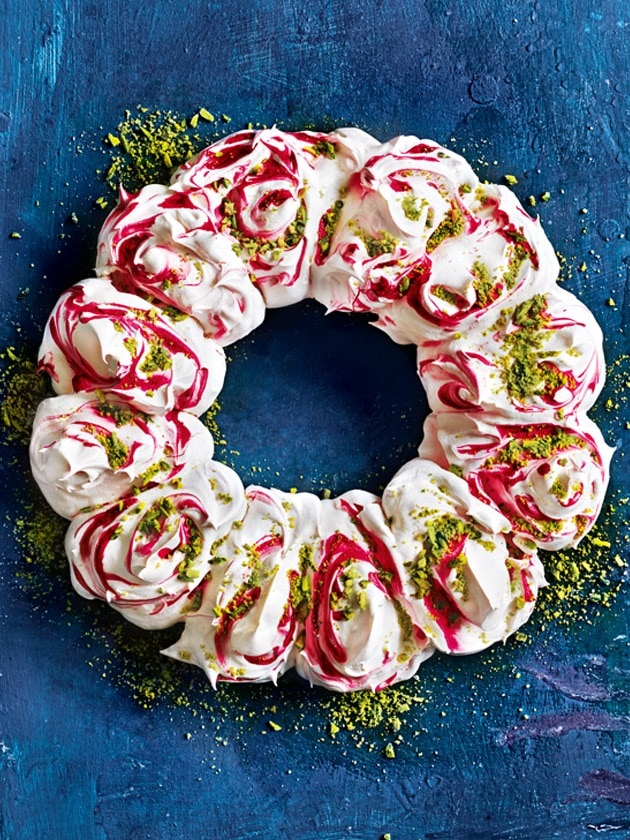 Raspberry swirl pavlova wreath sprinkled with chopped pistachios. 