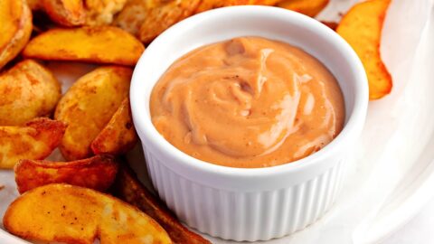 Plater of fried potato wedges with a bowl of dipping sauce.