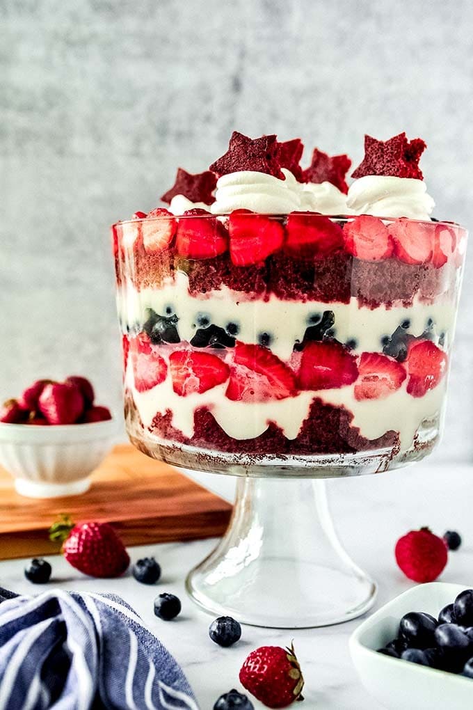 Red velvet trifle in huge glass bowl with fresh berries, red velvet cake, and cheesecake pudding.