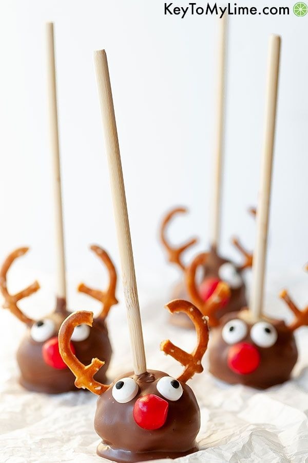 Reindeer-inspired chocolate cake pops on stick with pretzel antlers and candy eyes
